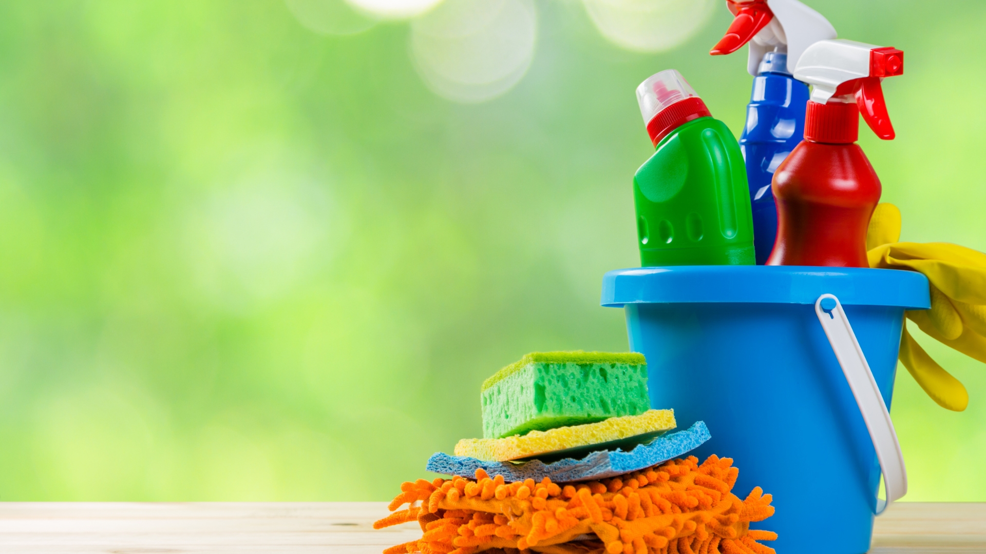 A bucket of cleaning supplies sitting on top of a wooden table