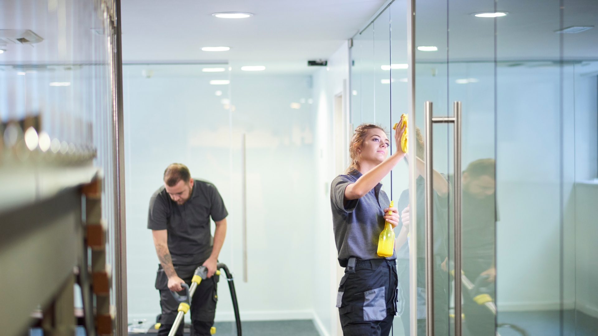 A man and a woman are cleaning a hallway